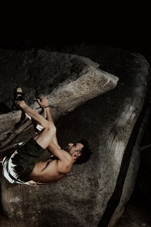 Man practicing rock climbing among large rocks in a forest