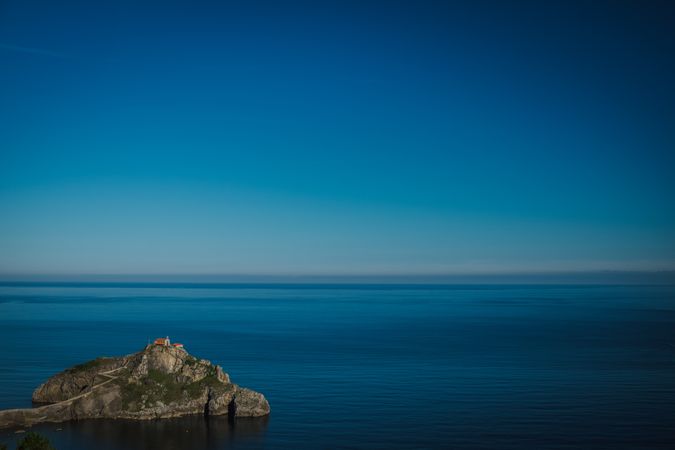 Lonely island amid sea tranquility under perfect blue sky