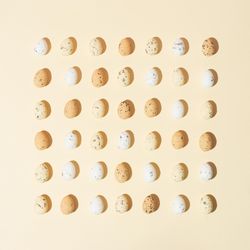 Speckled eggs  in rows on pastel yellow background