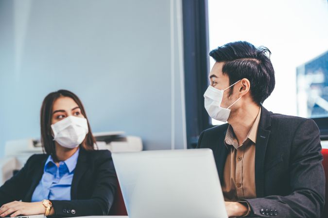 Two people chatting In face mask talking at office desks