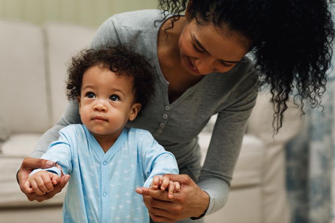 Mother behind toddler son as he learns to walk