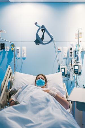 Female patient in mask lying on hospital bed