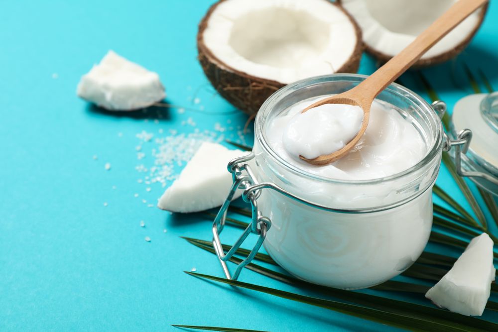 Coconut, palm branch and cosmetic on turquoise background. Tropical fruit