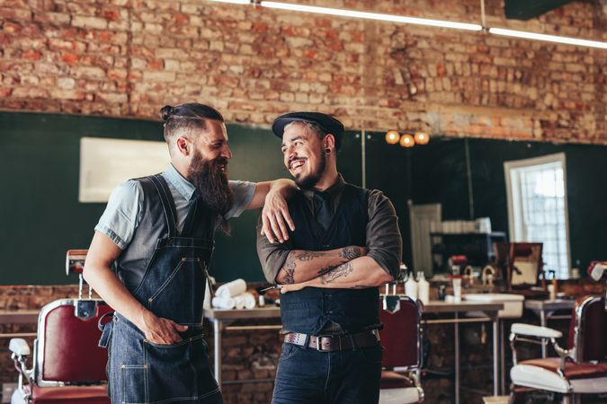 Two male barbers smiling in barbershop