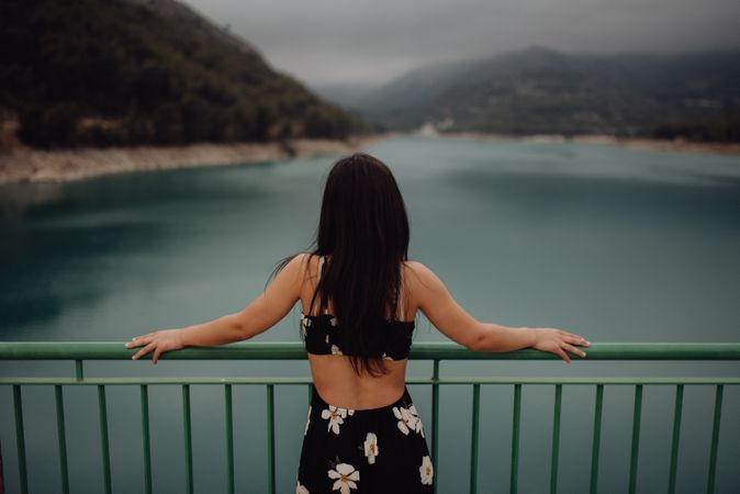 Relaxed woman in sundress enjoying view on bridge across wide river