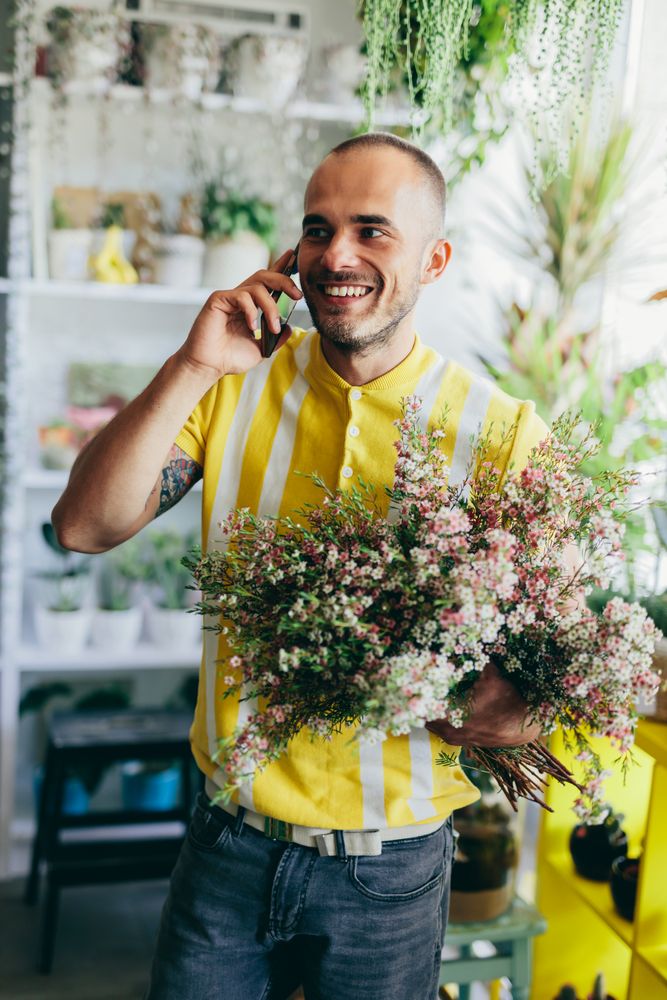 Man holding flowers, talking on the phone.