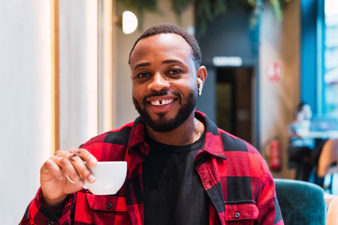 Smiling Black man with cup of coffee in cafe