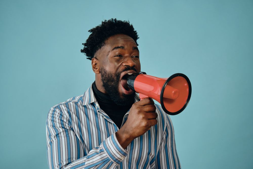 Portrait of a Black man in blue studio shoot with megaphone