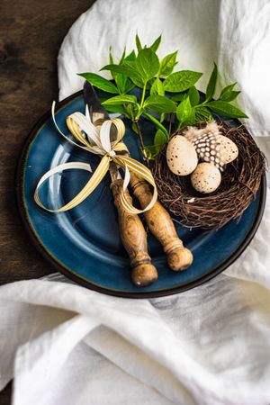 Easter table setting with nest and eggs on blue plate