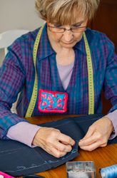 Older female seamstress sewing cloth