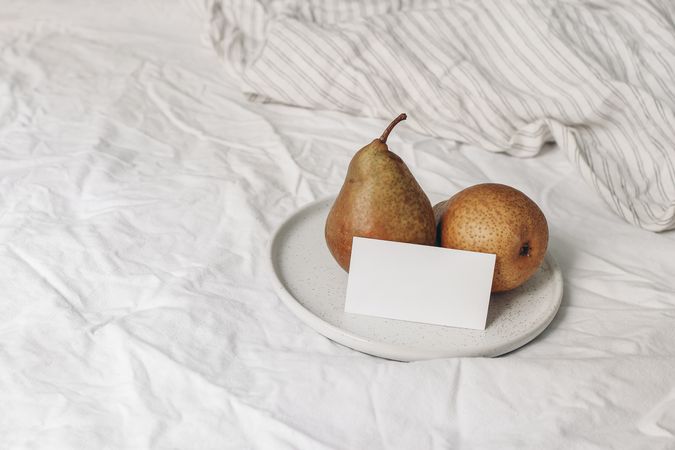 Blank business card mockup and pear fruit on ceramic plate