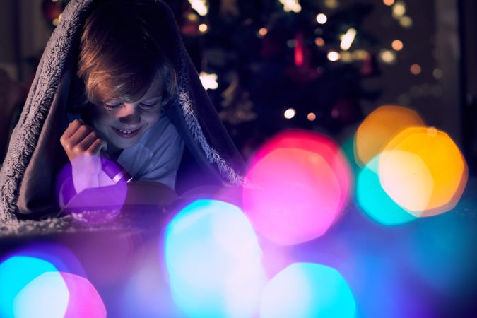 Positive boy reading book in dark room