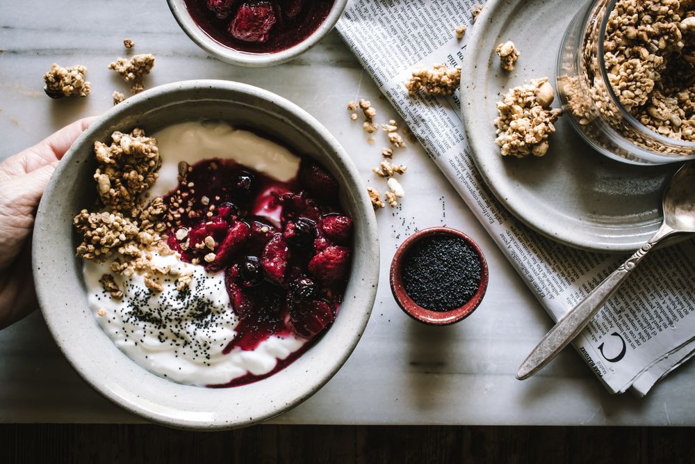 Delicious breakfast bowl with quinoa, rice and groats near tea cup and newspaper