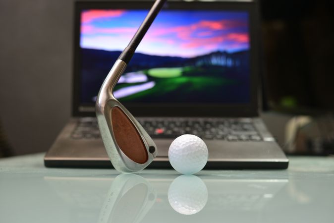 Golf club and ball in front of a laptop