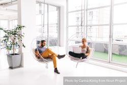 A man and woman working separately in a bright modern office R0JEZb