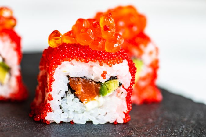 Sushi rolls with roe, avocado and salmon with copy space
