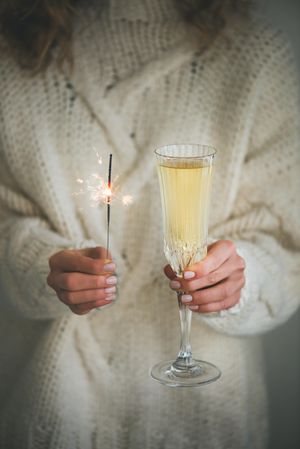 Woman holding crystal flute of champagne and sparkle and  sweater
