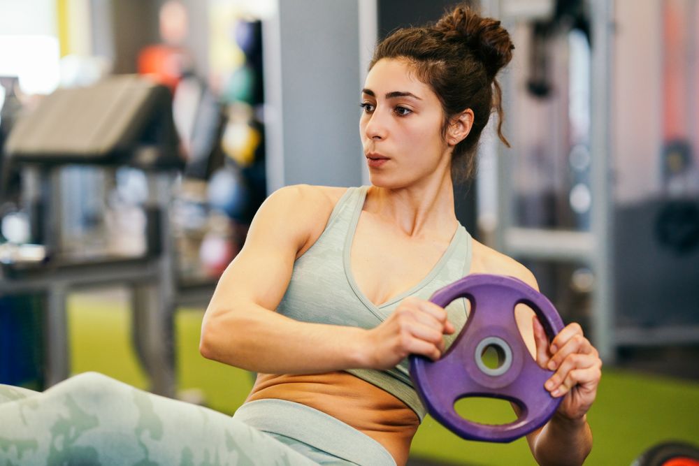 Woman exercising her abs in gym on mat with weight