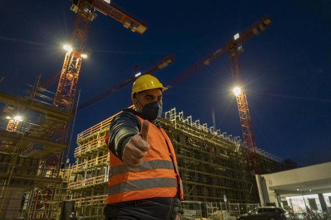 Engineer gesturing thumbs up outdoors at night