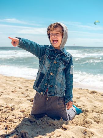 Happy boy pointing finger at distance on beach