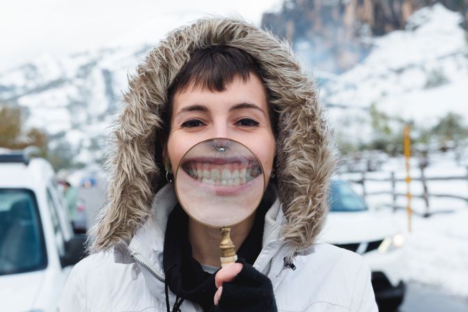 Woman smiling through magnifier in winter