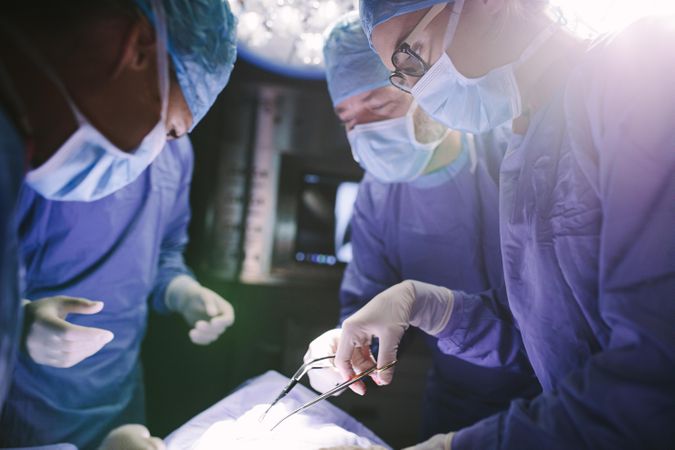 Female surgeon with her team performing surgery on patient in hospital operating room