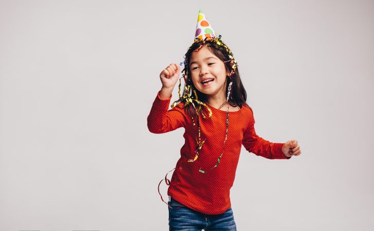 Playful child dancing and wearing gold ribbons on her head