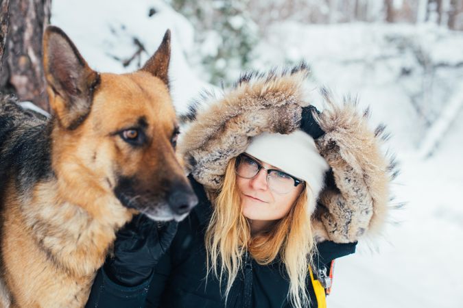 Blonde woman in winter parka on snowy day with dog