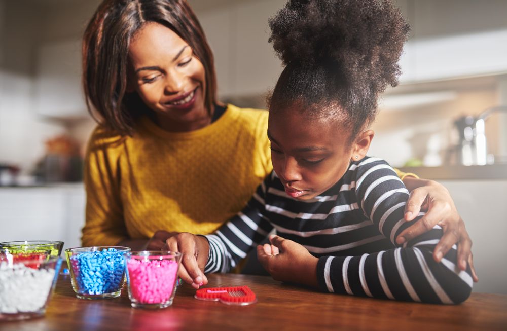 Smiling Black mother and daughter doing arts and crafts at home