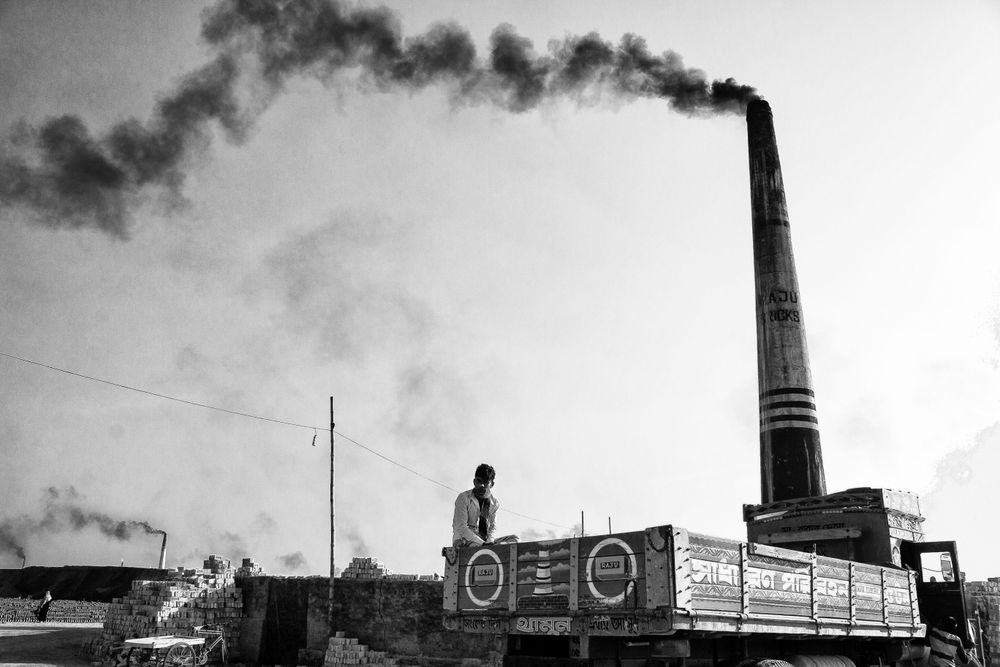 Grayscale photo of man sitting beside a chimney