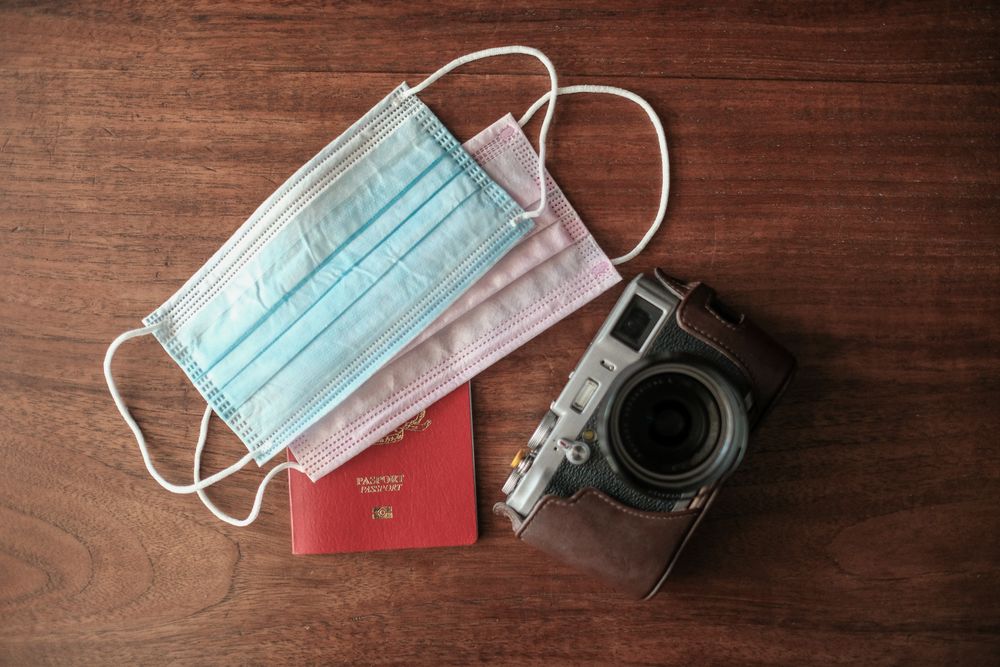 Overhead shot of facemasks, passport and camera on table