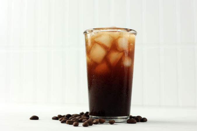 Iced Americano Coffee with Coffee Beans on Light Background