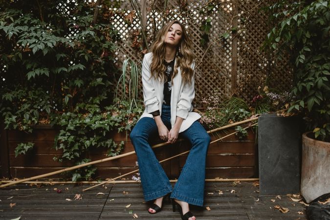 Woman sitting on planter in garden