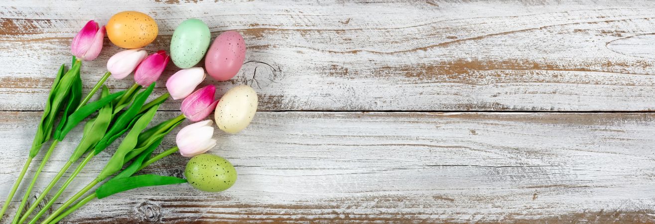 Colorful eggs and tulips for Easter holiday on rustic wooden background