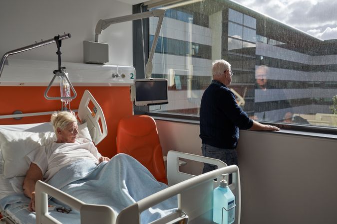 Thoughtful mature man standing near window during visit of unwe