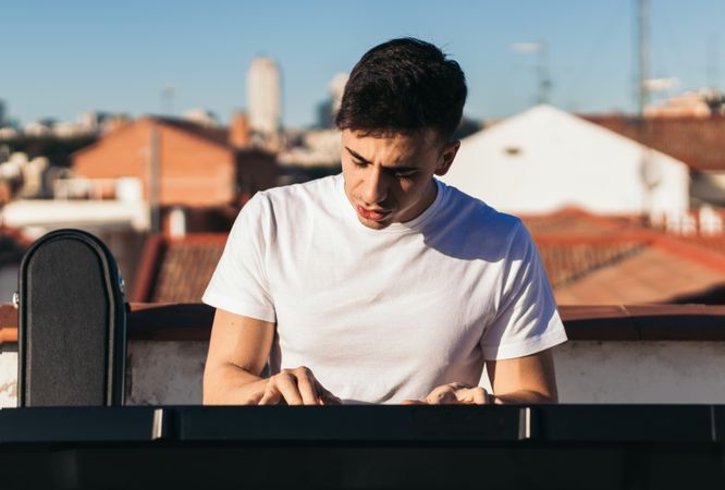 Front view of a man playing music keyboard on a rooftop