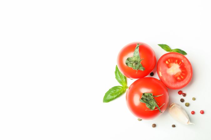 Fresh cherry tomatoes with basil, pepper and garlic on plain background, space for text and top view. Ripe vegetables