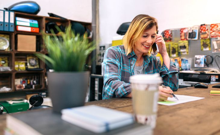 Smiling blonde young woman talking by cellphone in a store.