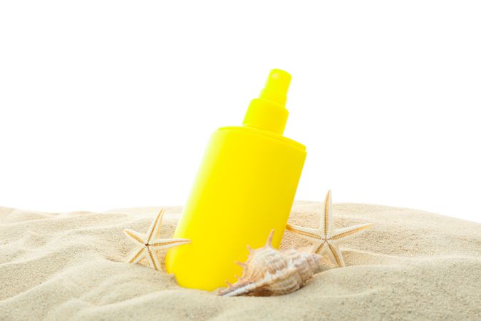 Sunscreen with starfish and seashells on clear sea sand isolated on plain background. Summer vacation