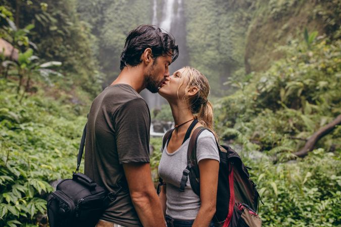Couple in love kissing near a waterfall in forest