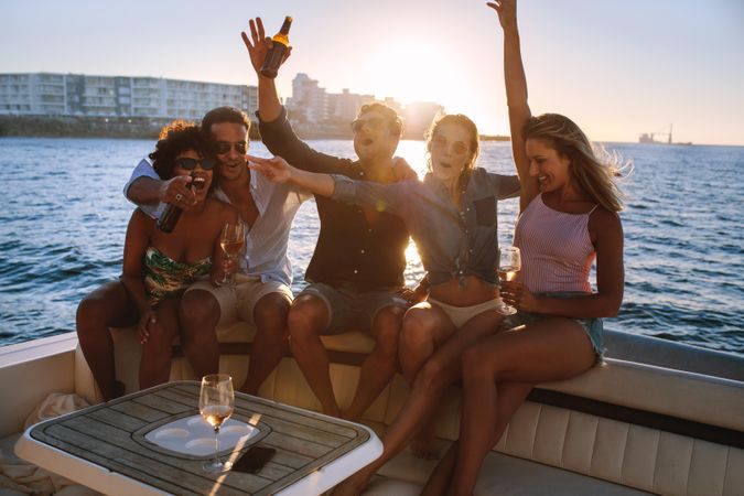Excited group of friends having fun on boat at sunset