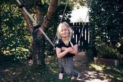 Smiling blonde girl with braided hair sitting on outdoor swing