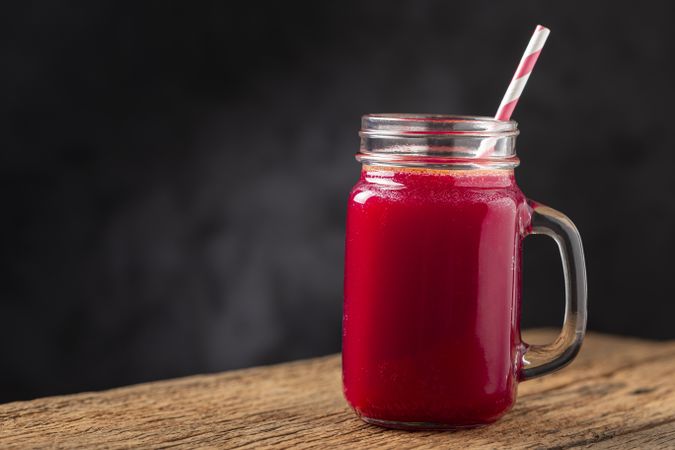 Red beet juice in a glass cup on the wooden table.