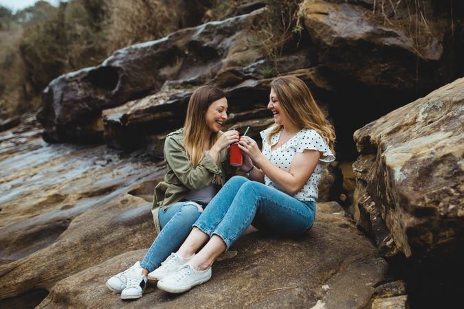 Young sisters sitting on stone on spring day