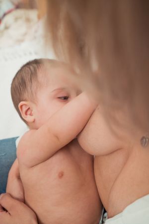 mother breast feeding and hugging baby
