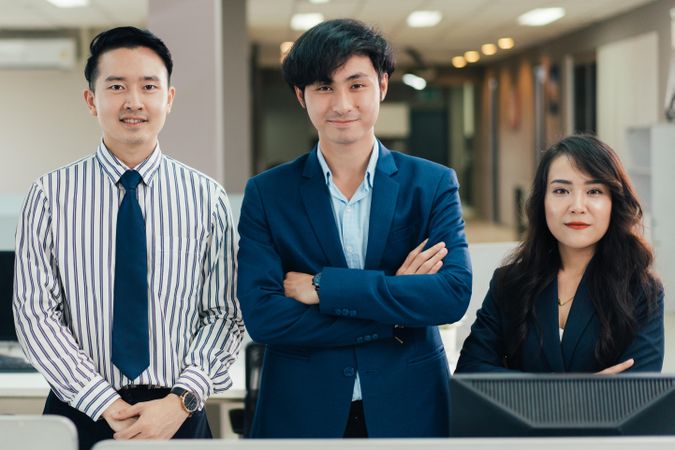 Group of Asian corporate business team with arms crossed looking at camera