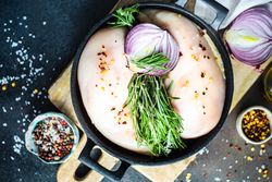 Top view of raw chicken in pan ready to cook on cutting board