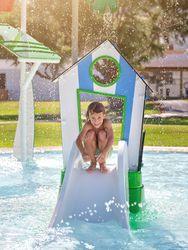 Smiling boy sitting on slide near water