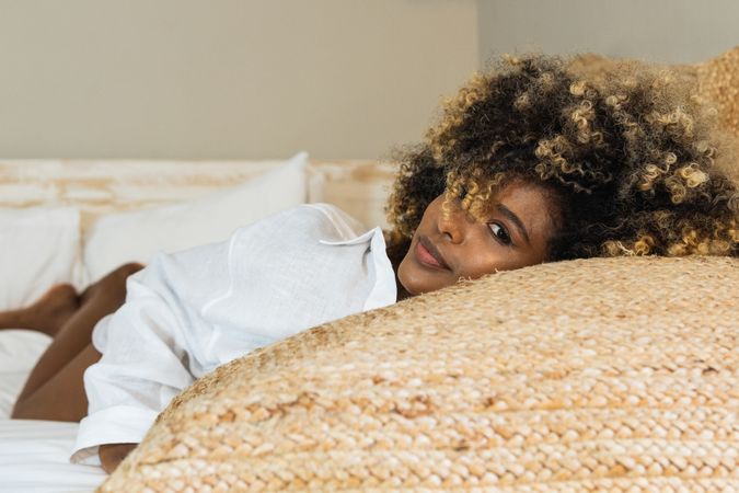 Thoughtful Black woman lying on bed in bedroom