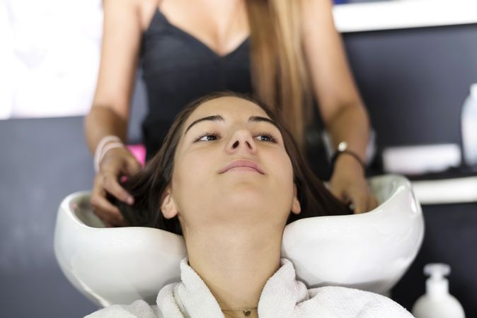Female sitting with head back in sink at hairdressers